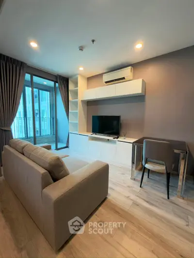 Modern living room with sleek furniture and large windows offering natural light and a view of the cityscape.