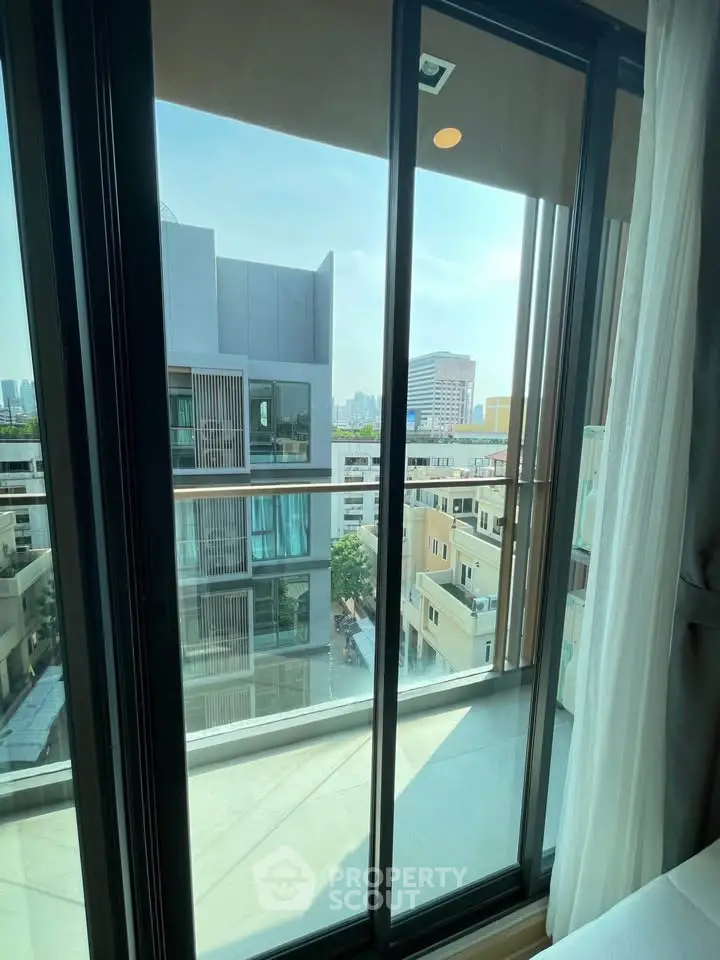 Stunning city view from modern apartment balcony with glass doors.