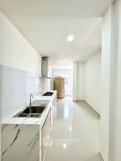 Modern kitchen with sleek white cabinetry and gas stove in a bright, minimalist apartment.