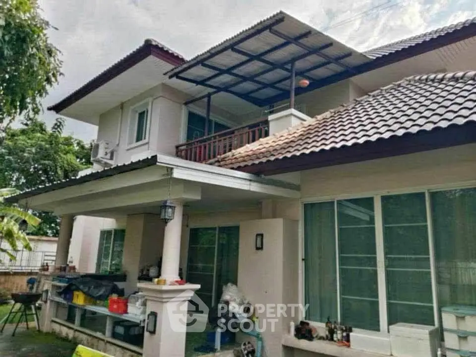 Charming two-story house with tiled roof and spacious balcony in lush green setting.