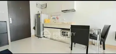 Modern kitchen with sleek cabinetry and dining area in compact apartment