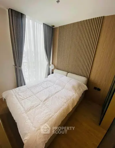 Modern bedroom with stylish wood paneling and large window for natural light.
