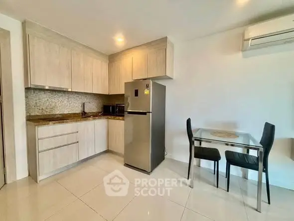 Modern kitchen with sleek cabinets, stainless steel fridge, and cozy dining area.