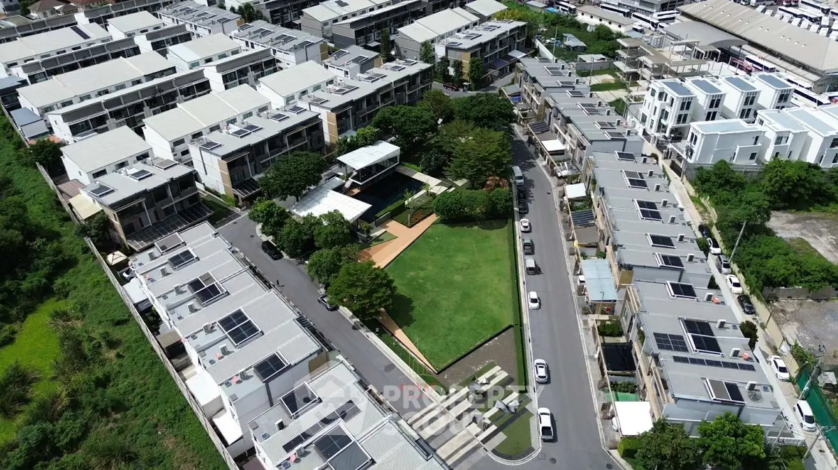 Aerial view of modern residential complex with green park and solar panels.