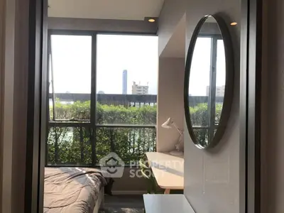 Modern bedroom with large window and study desk, offering natural light and city view.