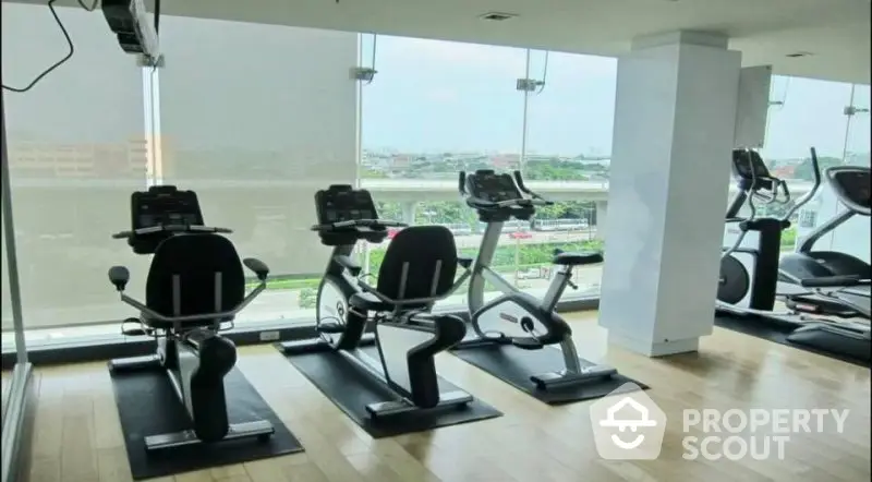 Modern gym with panoramic city views and state-of-the-art exercise equipment, perfect for fitness enthusiasts.