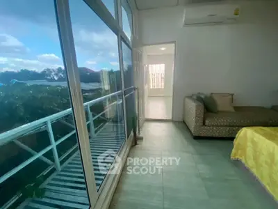 Bright living room with large windows and balcony view, featuring modern sofa and air conditioning.