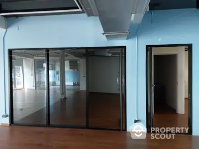 Spacious commercial space with large glass partitions and wooden flooring, ideal for businesses seeking an open layout with private rooms.