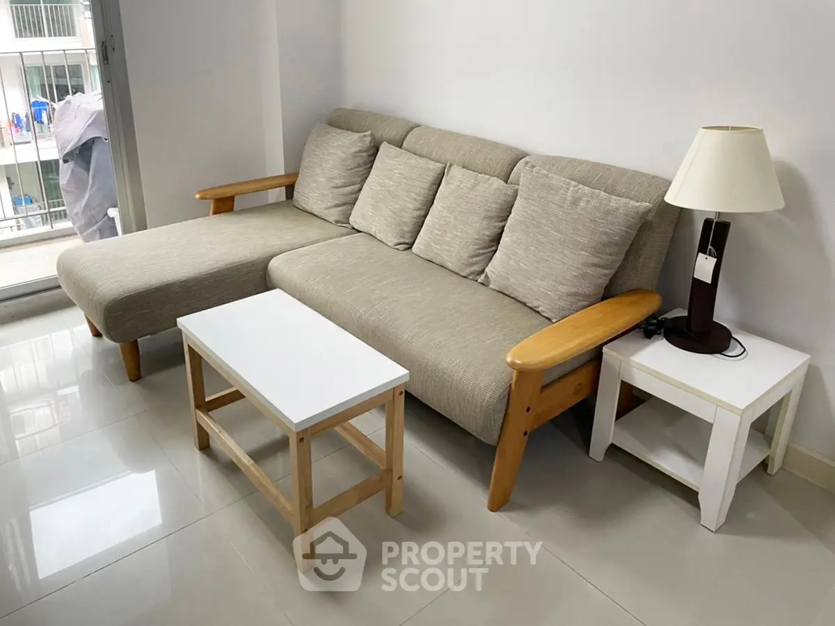 Modern living room with cozy beige sofa and sleek coffee table near balcony.