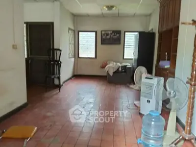 Spacious room with tiled floor, windows, and basic furnishings in a residential property.