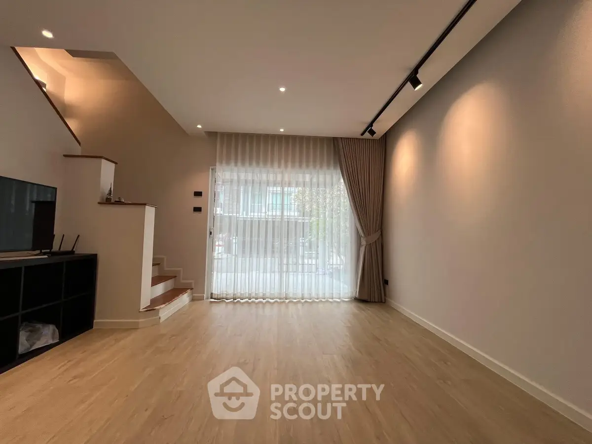 Spacious modern living room with large window and elegant staircase