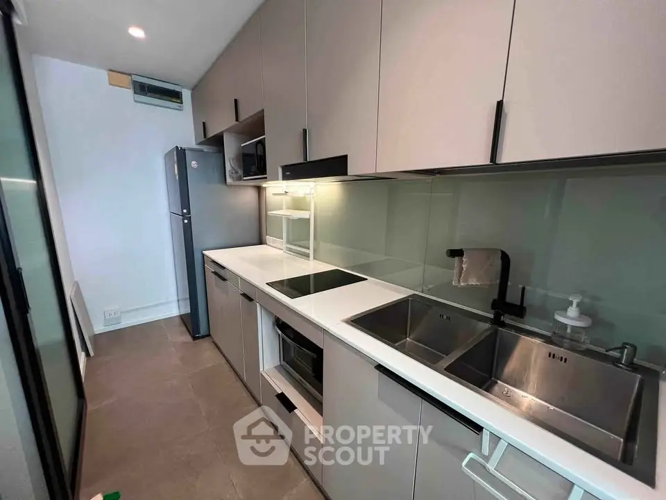 Modern kitchen with sleek cabinetry, built-in appliances, and glass backsplash in a contemporary apartment.
