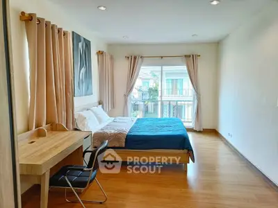 Spacious bedroom with modern decor and large window offering natural light.