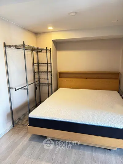 Modern minimalist bedroom with wooden bed frame and metal shelving unit.