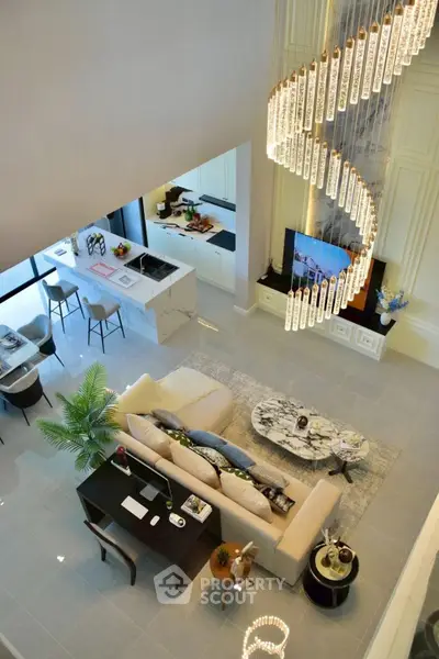 Luxurious open-plan living room with elegant spiral chandelier and modern kitchen.