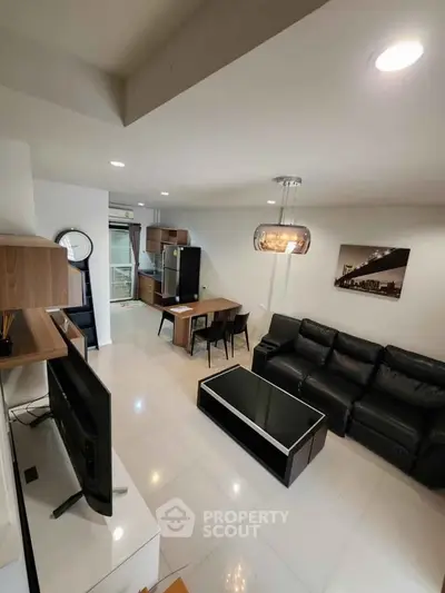 Modern living room with sleek furniture and open layout, featuring a stylish black sofa and dining area.