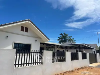 Charming single-story house with modern fence under clear blue sky, perfect for family living.