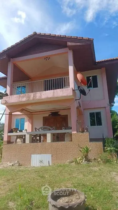 Charming two-story house with spacious balcony and lush garden view.