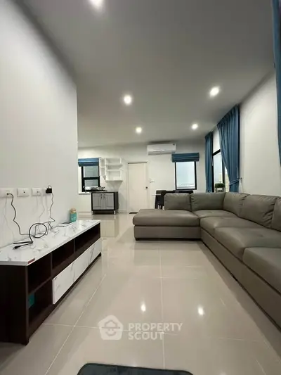 Spacious modern living room with sleek furniture and ample natural light.