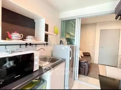 Compact kitchen with modern appliances and cozy living area in stylish apartment.