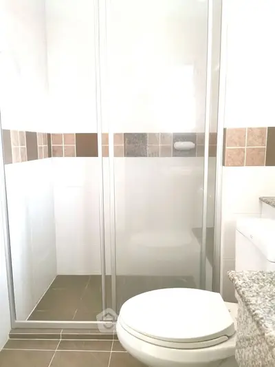 Modern bathroom with glass shower and tiled walls in a bright setting.