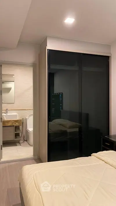Modern bedroom with ensuite bathroom and sleek black wardrobe doors.