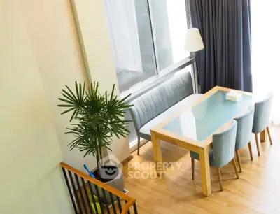 Modern dining area with glass table, stylish chairs, and large window for natural light.