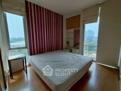Modern bedroom with large windows and striped accent wall, offering a bright and airy atmosphere.