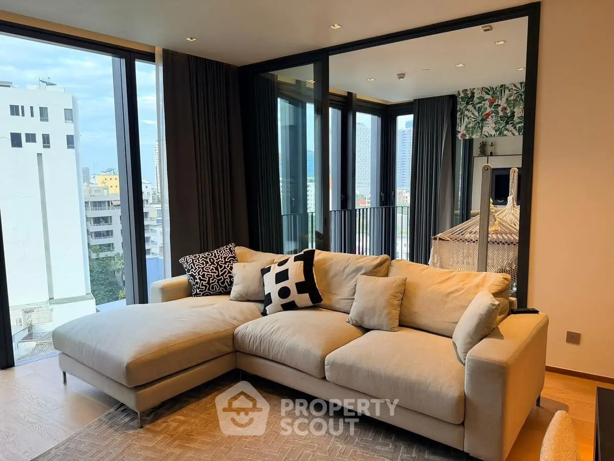 Luxurious living room with modern L-shaped sofa and city view balcony.