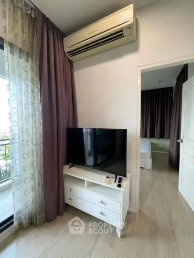 Modern apartment interior with TV, air conditioning, and bedroom view.