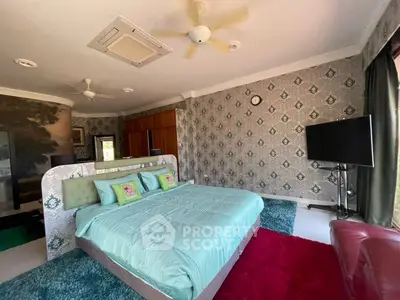 Spacious bedroom with modern decor and large TV, perfect for relaxation.