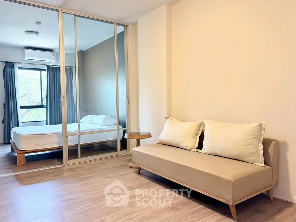 Modern apartment interior with cozy living room and bedroom separated by glass doors.