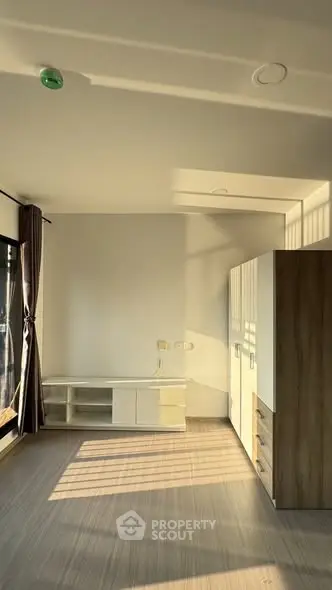 Spacious sunlit room with modern wardrobe and entertainment unit, perfect for stylish living.