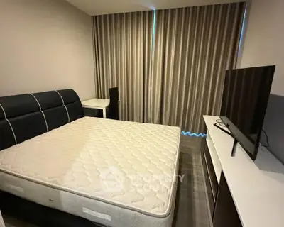 Modern bedroom with large bed, sleek TV stand, and elegant curtains in a cozy apartment.
