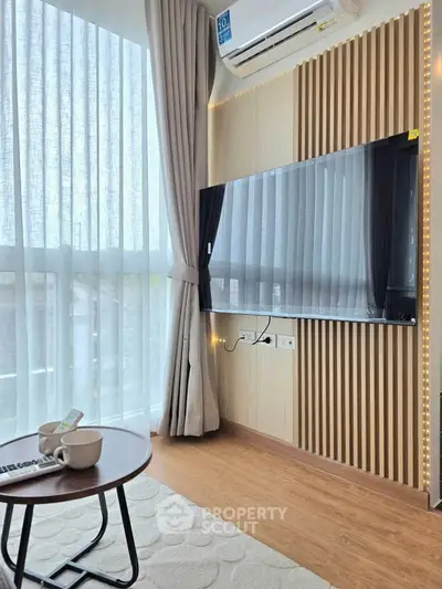 Modern living room with large TV, air conditioning, and natural light from floor-to-ceiling windows.