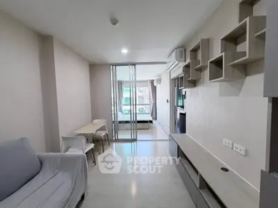 Modern living room with sleek furniture and sliding glass doors leading to a bedroom, perfect for urban living.