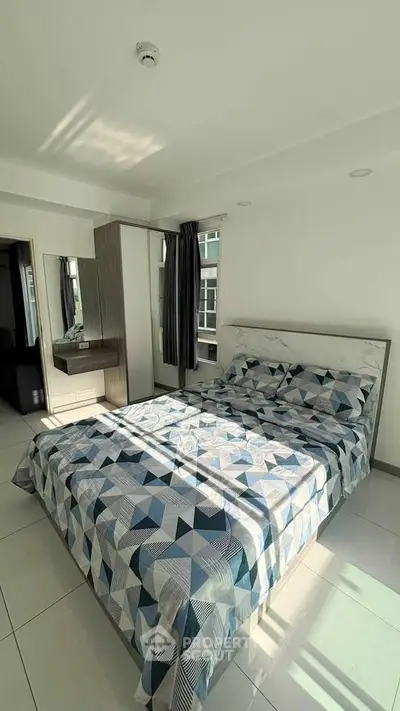 Bright and modern bedroom with stylish geometric bedding and ample natural light.