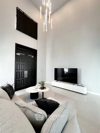 Modern living room with high ceiling, elegant chandelier, and sleek TV setup