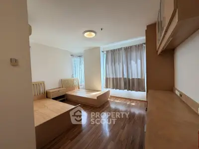 Spacious bedroom with wooden flooring and ample natural light