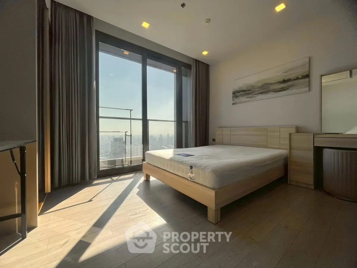 Spacious bedroom with large windows offering stunning city views and modern furnishings.