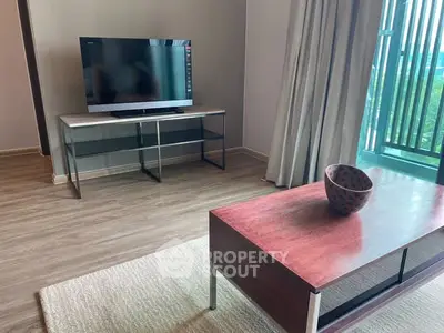 Modern living room with TV and stylish coffee table, featuring floor-to-ceiling windows.