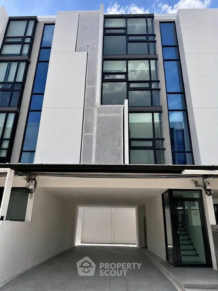Modern multi-story building with sleek glass facade and open parking area.
