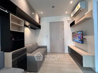 Modern living room with sleek furniture and wall-mounted TV, featuring stylish shelving and air conditioning.