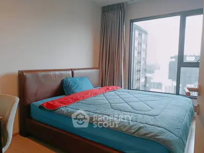 Modern bedroom with large window offering city view, featuring stylish bed and cozy decor.