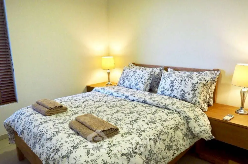 Cozy bedroom with floral bedding and warm lighting, perfect for relaxation.