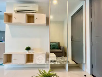 Modern living room with sleek furniture and mirrored wall for spacious feel.