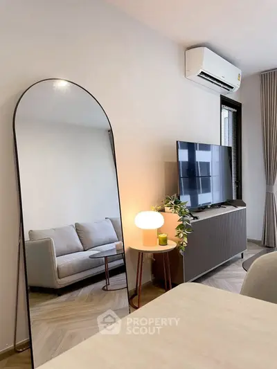 Modern living room with stylish decor, featuring a large mirror and sleek furniture.