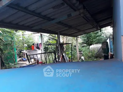 Outdoor covered area with laundry and greenery, potential for renovation.