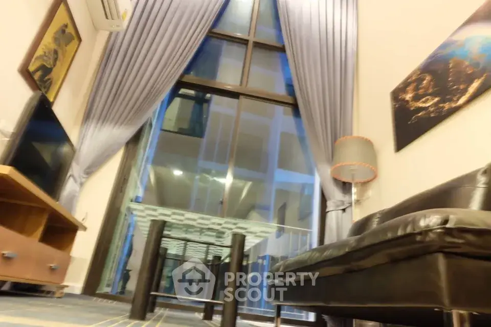 Luxurious living room with high ceilings and large windows offering stunning views.