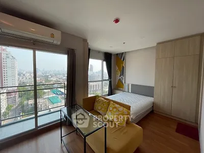 Modern studio apartment with city view, featuring cozy living area and large windows.